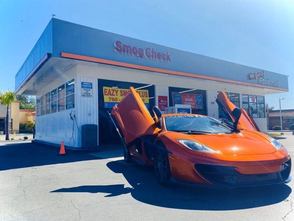 A orange car is parked in front of a building.