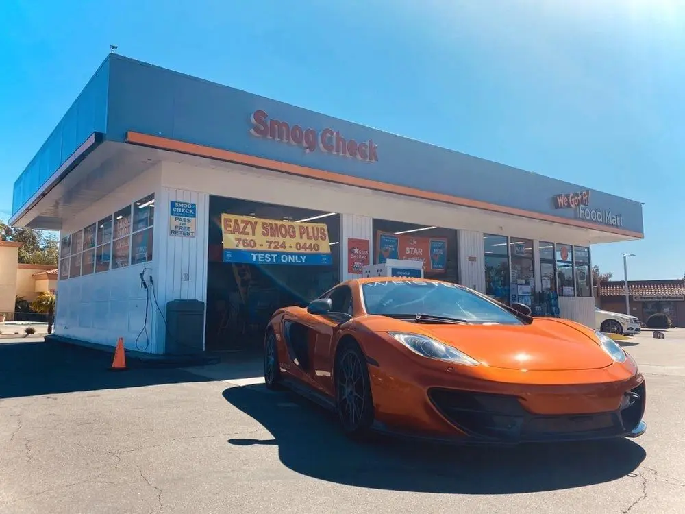 A orange car parked in front of a service station.